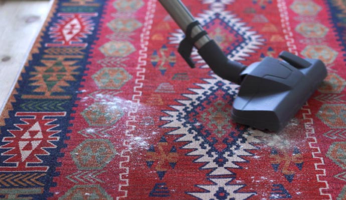 a professional vacuuming a rug using equipment