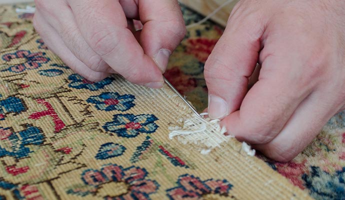 Person repairing rug with equipment