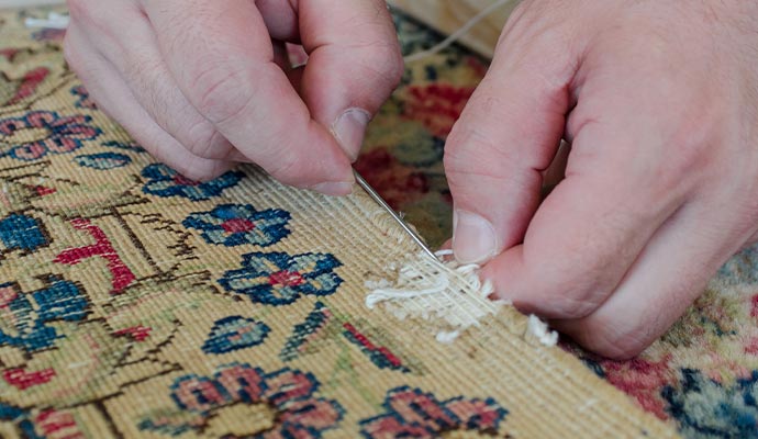 Person repairing rug  with equipment