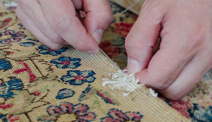 Expert repairing moth damaged rug.