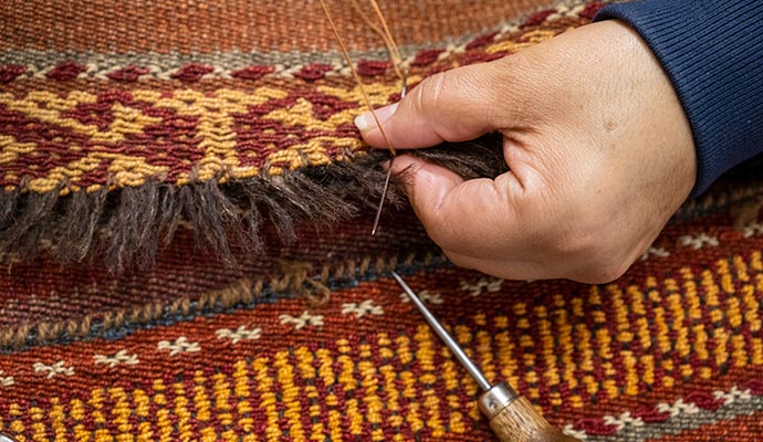 Expert repairing rug using equipment.