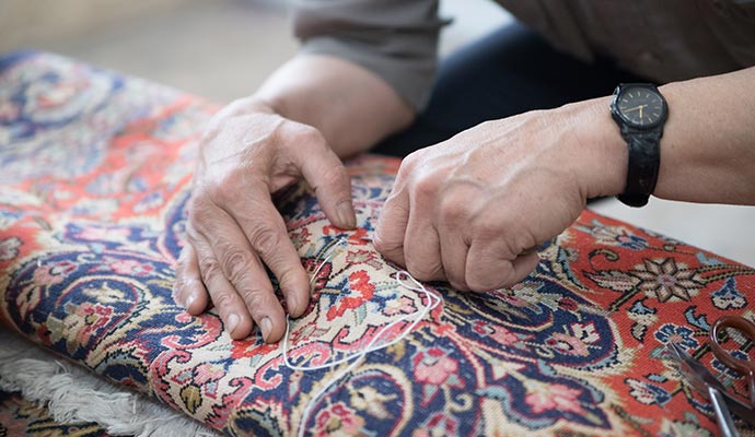 Person repairing rug  with equipment