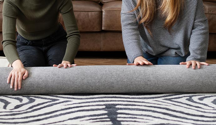 two people rolling up a rug